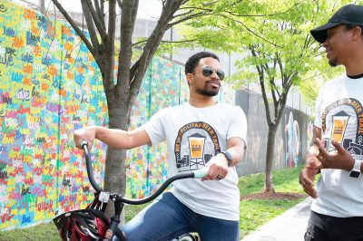 bikers enjoying the metropolitan beer trail in front of colorful mural