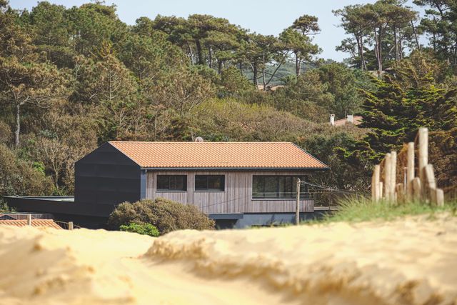 Depuis la dune, qui la sépare du fracas de l'océan, la villa Arranca et son bardage de bois sombre semblent ne faire qu'un avec la forêt de pins.