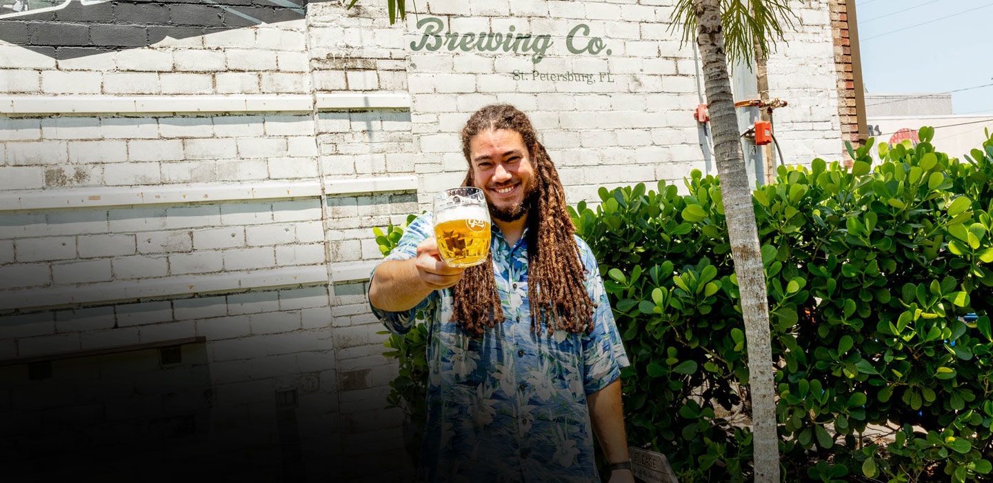 man holding stein glass outside green bench brewing co