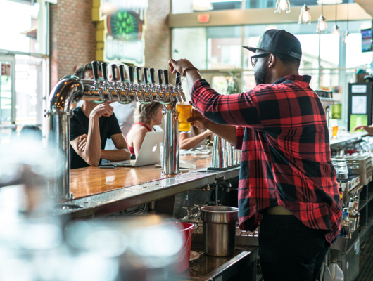 person pouring beet from bar tap