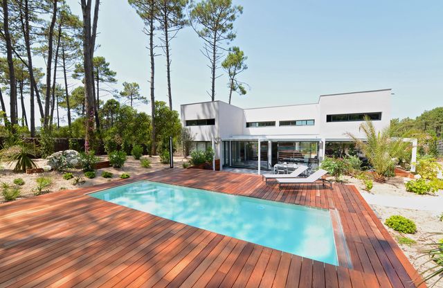 Piscine de 24m2 située en bord de plage, dans un environnement sauvage avec de grands pins. Piscine construite en béton armé monobloc, elle vient parfaitement s'intégrer dans ce décor naturel qui caractérise les landes : le sable prendre naturellement possession du jardin ; elle nous donne la sensation d'être en vacances sur une île déserte. La piscine possède un volet mobile rigide qui recouvre entièrement la piscine, pratique pour créer une immense terrasse. Son revêtement minéral est un Plaster® Blanc à base de purs cristaux de marbre de carrare. Diffazur Piscines.